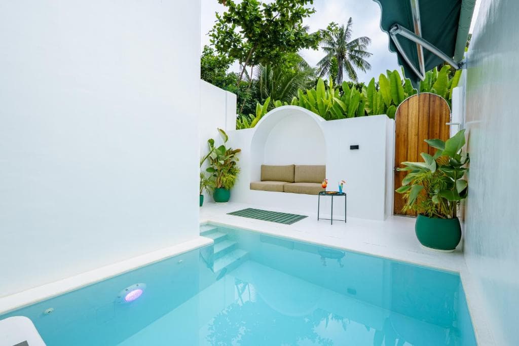 Private pool with built-in arched sofa nook and tropical palms